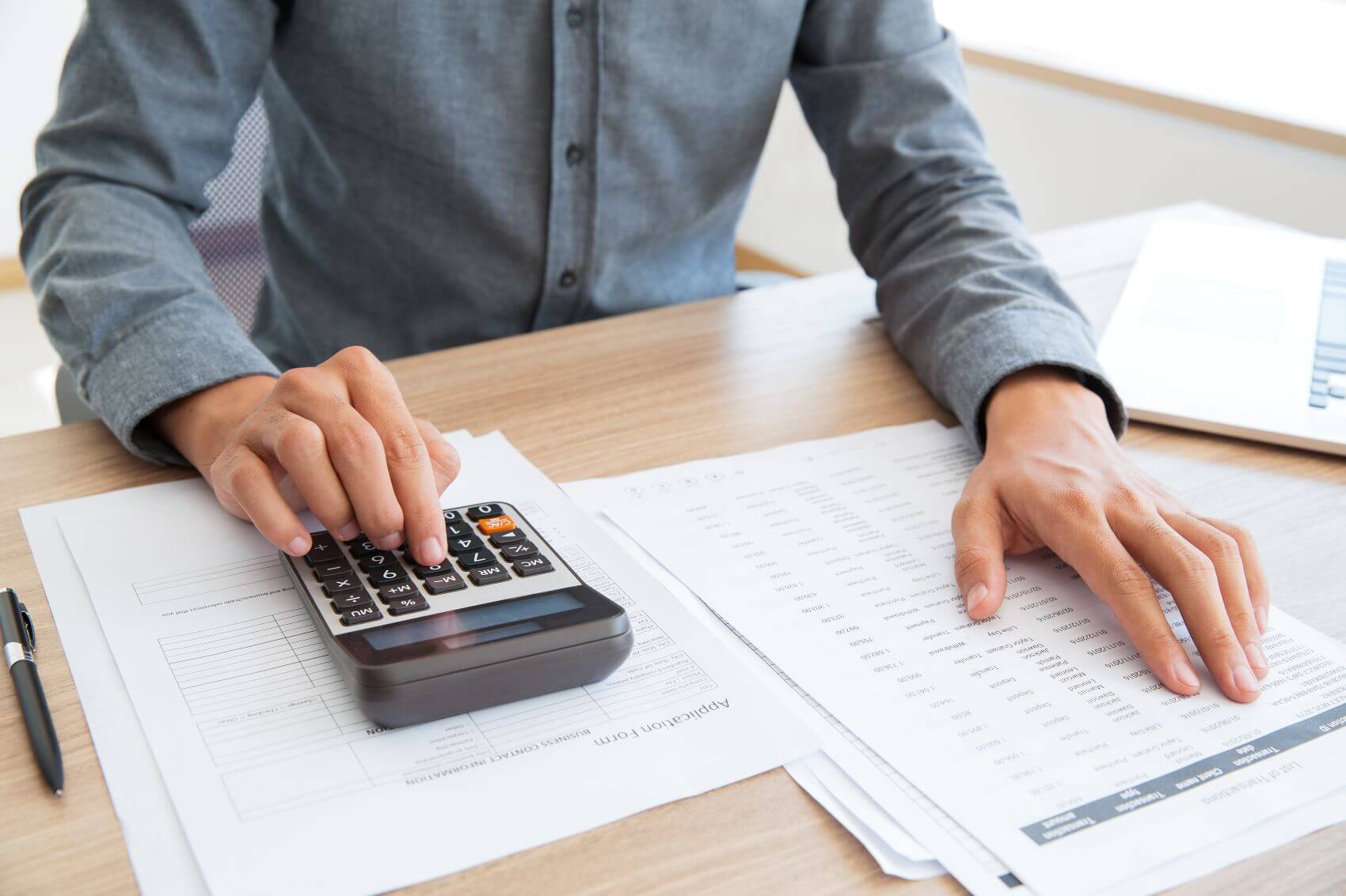 A man sat at a desk with a notebook and a calculator