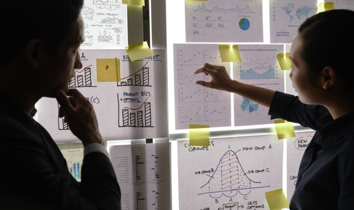 Financial managers analyzing financial reports and charts hanging on the wall