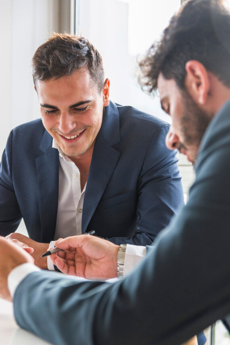 two business men smiling and using the calculator and talking
