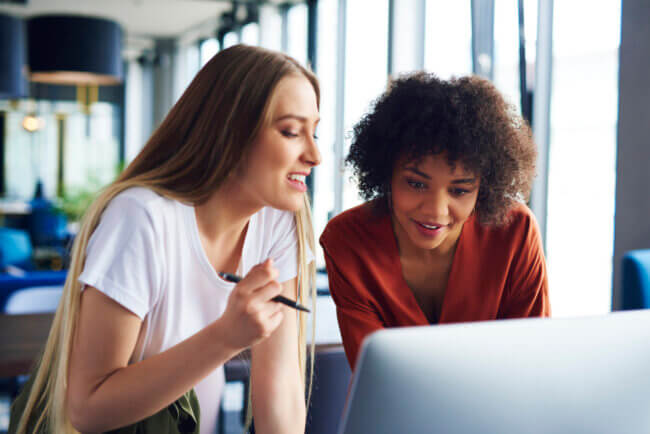 two women discussing business at a desk looking at the laptop.