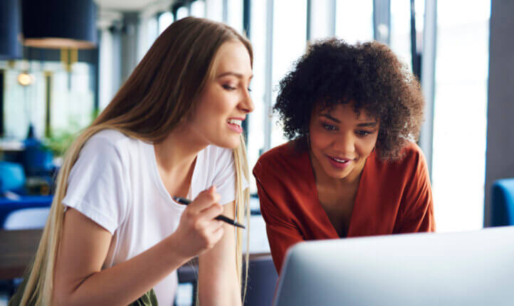two women discussing business at a desk looking at the laptop.