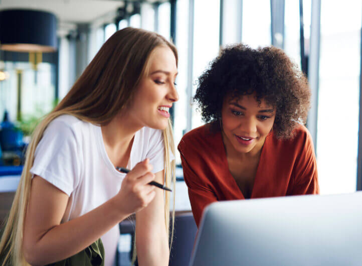 two women discussing business at a desk looking at the laptop.