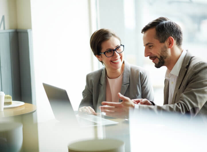 Two business people sitting by laptop discussing business